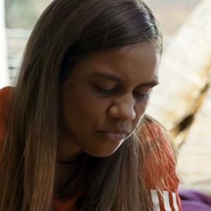 Close up of a teenage First Nations girl looking downwards.